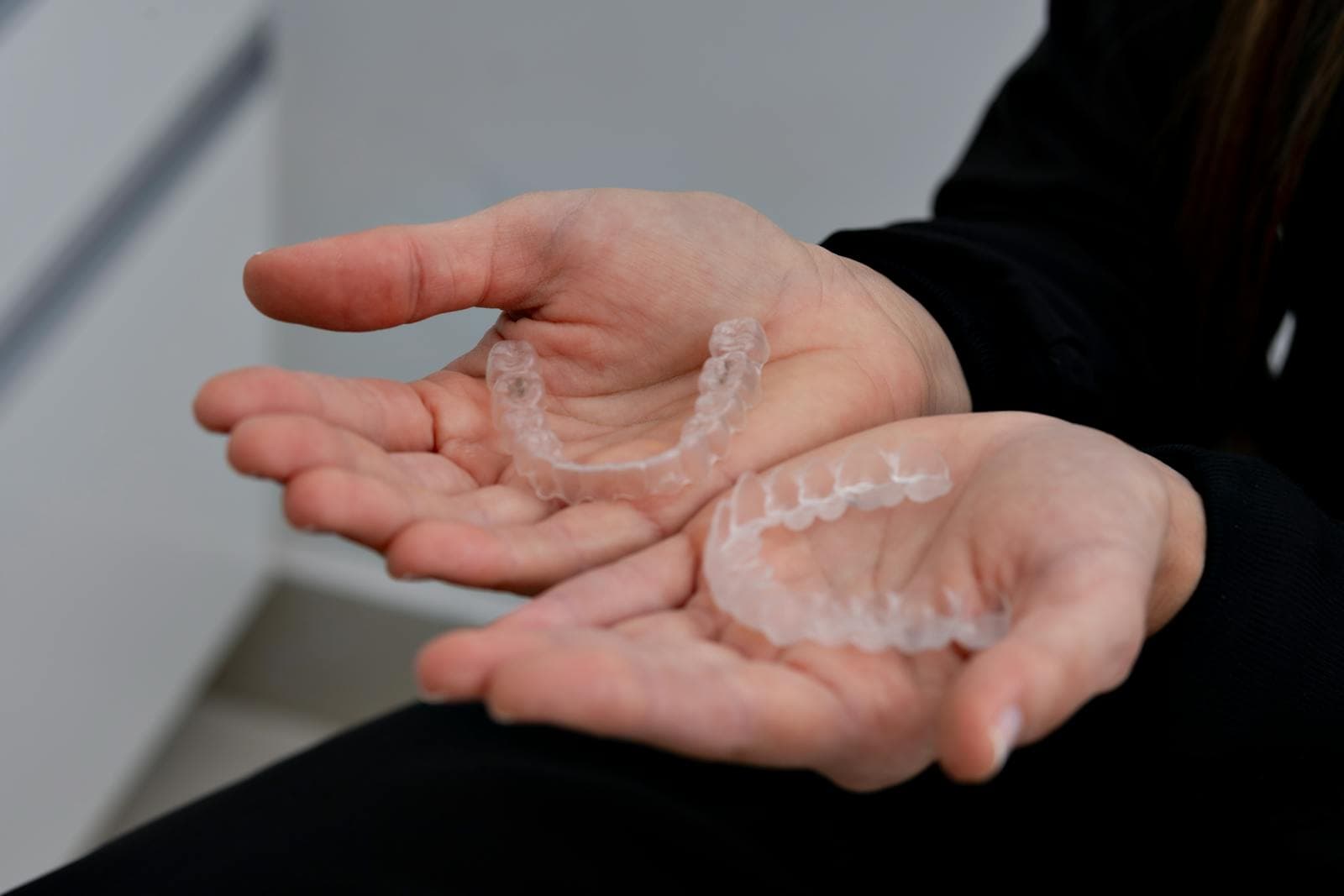 Hands holding clear aligners in a dental clinic